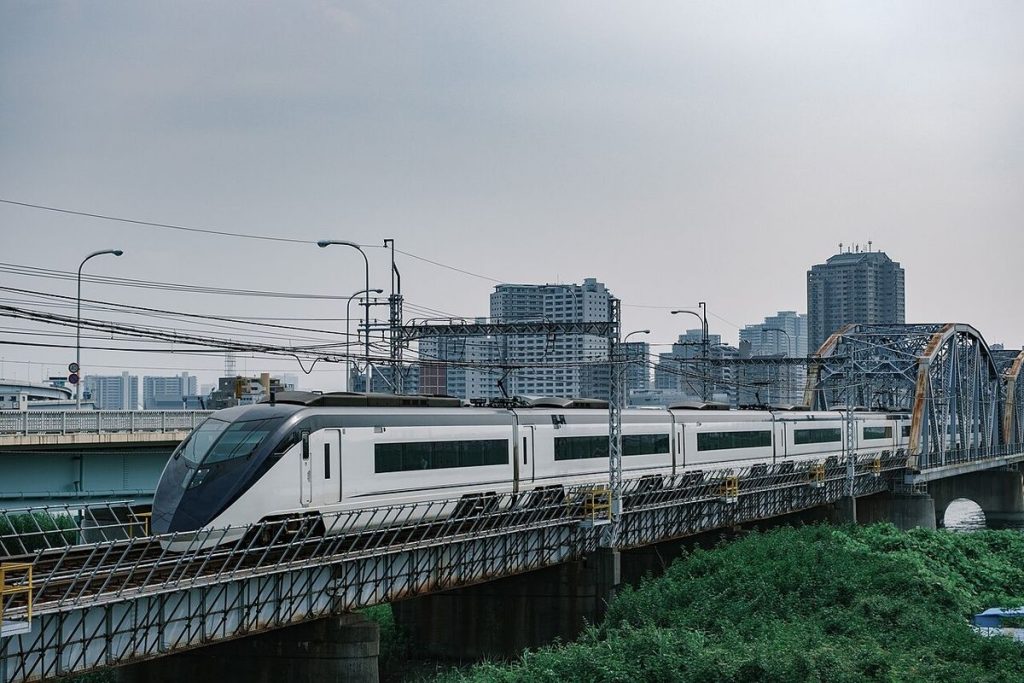 A white and blue Keisei AE Skyliner train crossing a bridge on the Keisei Main Line