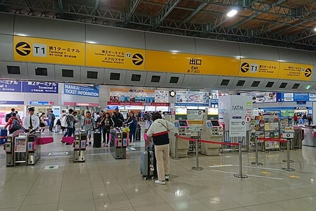 Row of automatic fare gates and ticket machines at Kansai Airport Station under yellow JR signs