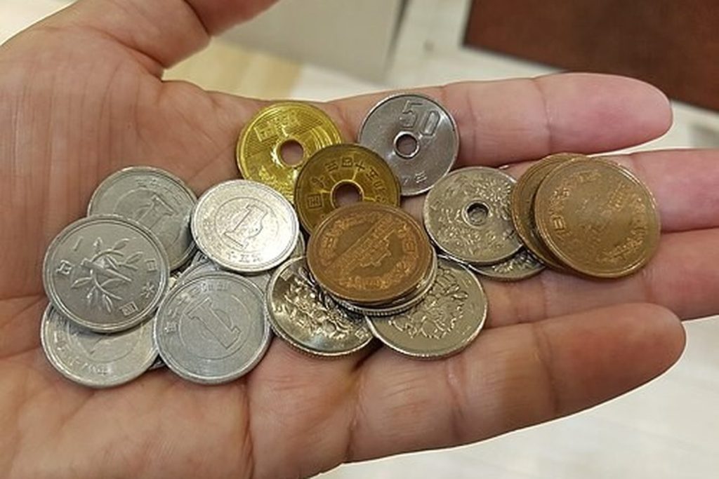 A handful of Japanese yen coins, including 500, 100, 50, 10, 5 and 1 yen pieces, held in an open palm