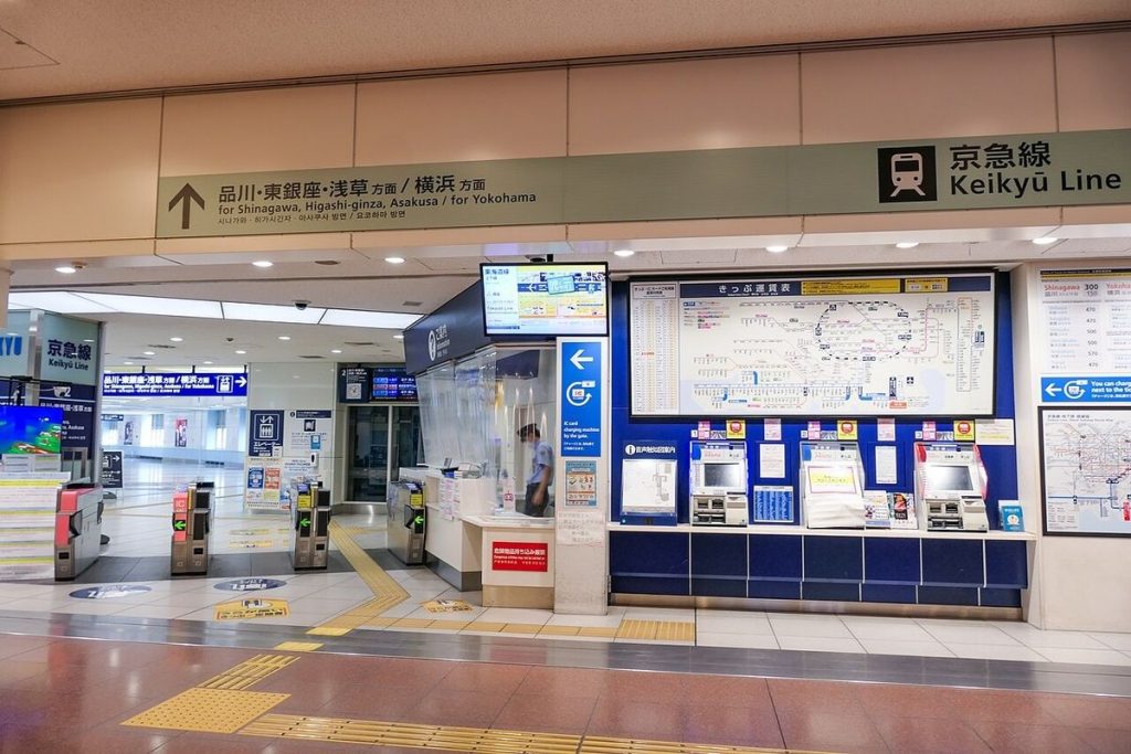 Keikyu Line ticket gates and ticket machines at Haneda Airport Terminal 3 Station under a sign pointing to Shinagawa, Higashi-ginza and Asakusa, or Yokohama