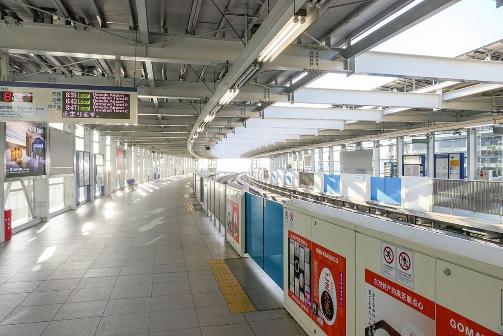 Bright, wide Tokyo Monorail platform at Haneda Airport Terminal 3 Station with platform screen doors and departure boards
