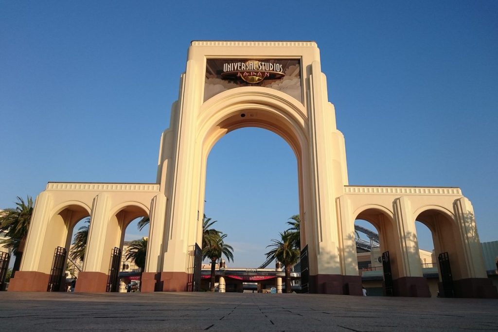 The cream-colored arched main entrance gate of Universal Studios Japan in Osaka under a clear blue sky