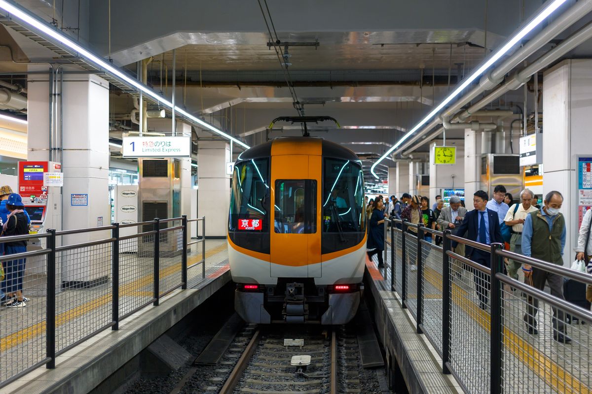 An orange-and-white Kintetsu Limited Express train waiting at a platform of Kintetsu Kyoto Station