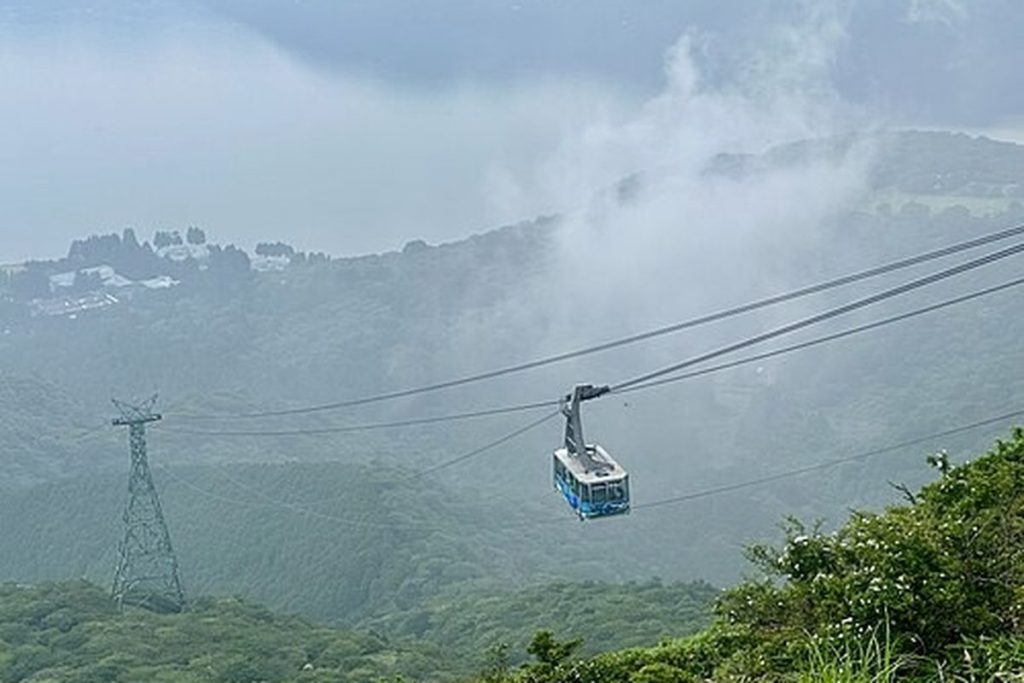 Hakone Ropeway gondola crossing a valley with cloud and green hills