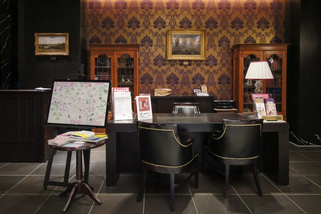 Hotel lobby desk in Kyoto with leather chairs, a city map on an easel and leaflets on a small table