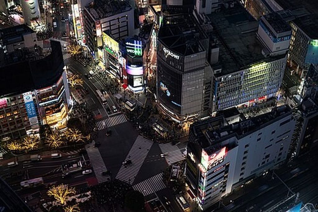 Shibuya Scramble Crossing seen from high above at night with buildings and lit signs