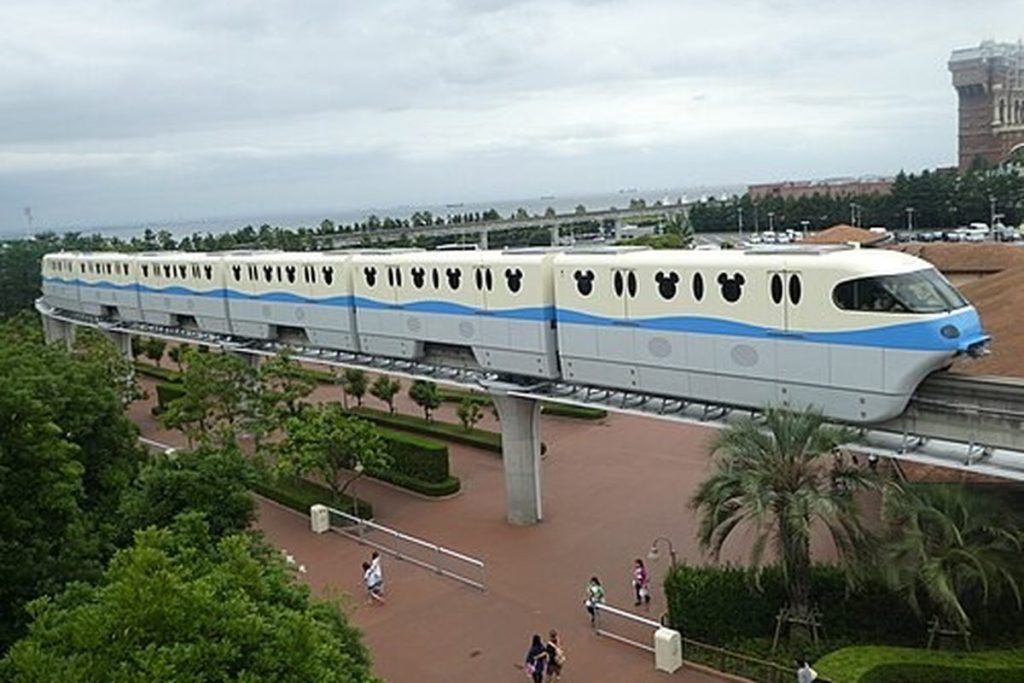 Disney Resort Line monorail train running on an elevated track above trees near Maihama