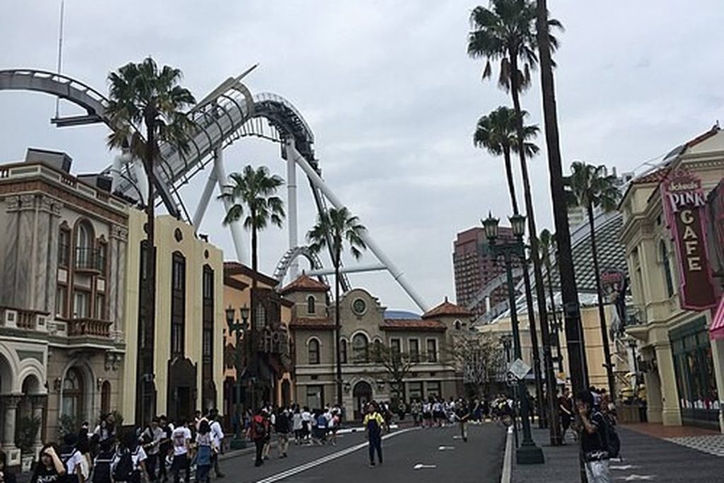 Palm-lined Hollywood Area street at Universal Studios Japan with a coaster track above the buildings