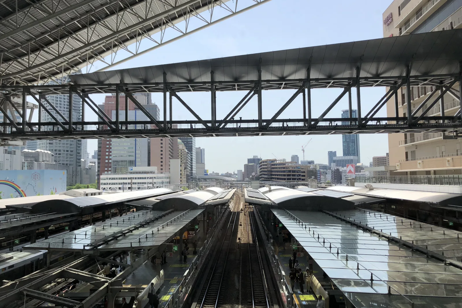 Osaka Station’s platform roofs and tracks seen from an upper-level walkway, under the station’s large overhead roof